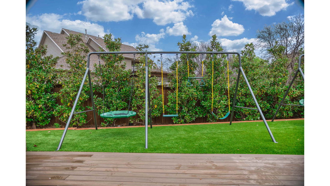 A large metal swing set on turf in a backyard on a semi-cloudy day.