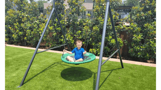 A child swinging on a green round swing attached to the gobaplay Single Swing Set.